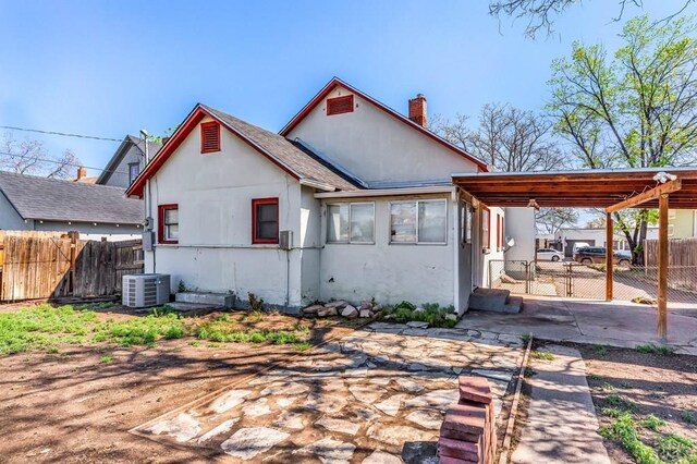 710 Wilson Ave, Pueblo, CO 81004 - rear view of property featuring a chimney, fence, stucco siding, and central AC