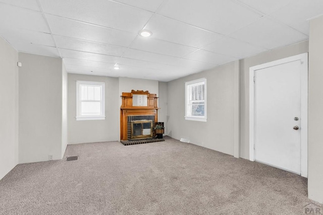710 Wilson Ave, Pueblo, CO 81004 - unfurnished living room featuring a brick fireplace, carpet, and a drop ceiling