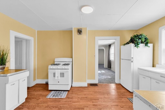 710 Wilson Ave, Pueblo, CO 81004 - kitchen featuring white appliances, light wood-style floors, white cabinets, light countertops, and baseboards
