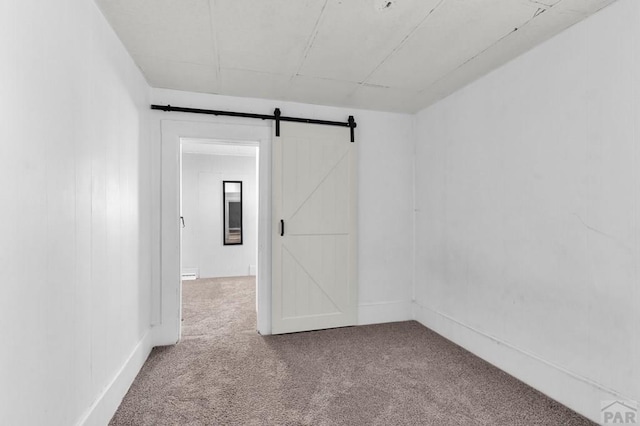 710 Wilson Ave, Pueblo, CO 81004 - carpeted empty room featuring a barn door and baseboards