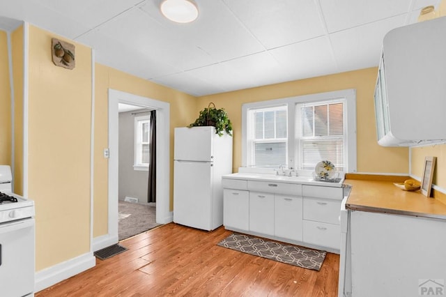 710 Wilson Ave, Pueblo, CO 81004 - kitchen with white appliances, light wood-style flooring, white cabinets, and light countertops