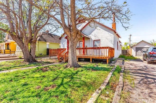 710 Wilson Ave, Pueblo, CO 81004 - back of property featuring an outdoor structure, a chimney, a wooden deck, stucco siding, and driveway