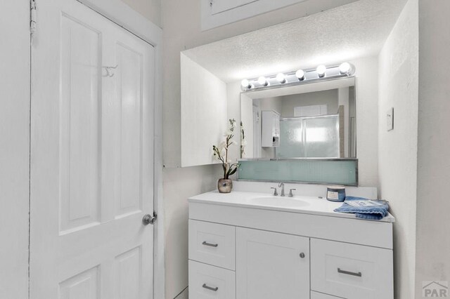 710 Wilson Ave, Pueblo, CO 81004 - bathroom featuring vanity, a shower with shower door, and a textured ceiling