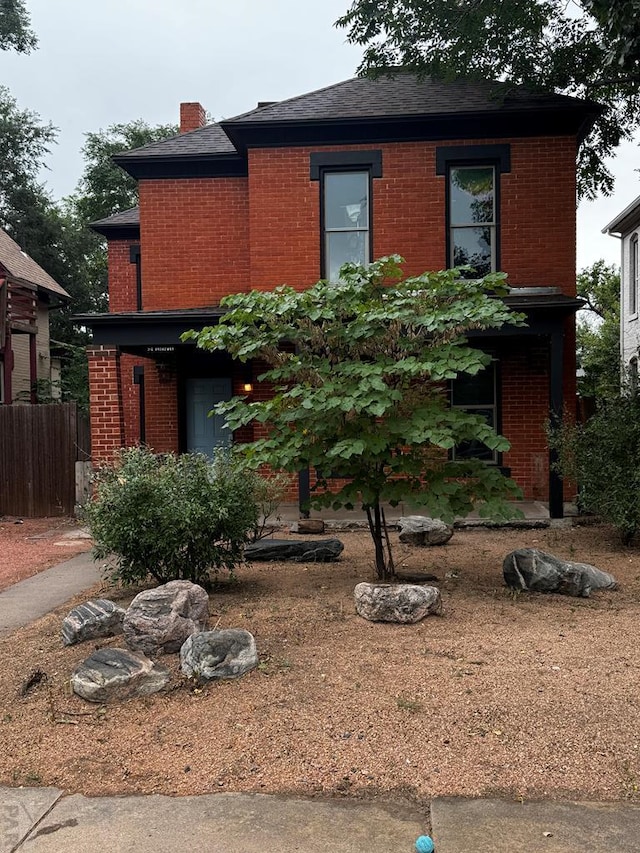 view of front facade with brick siding and a chimney