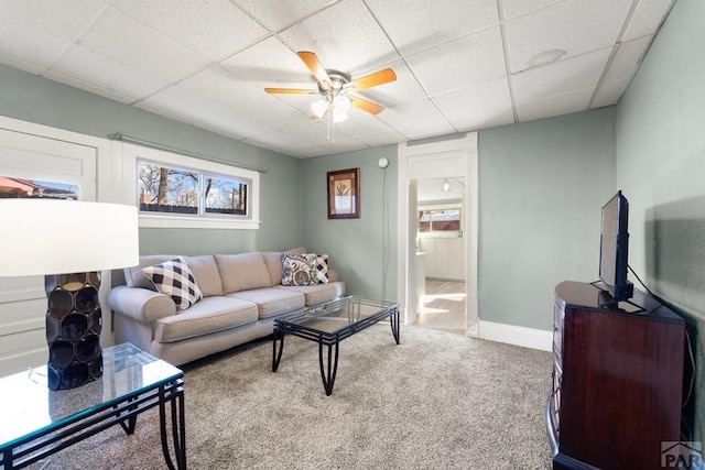 living area featuring ceiling fan, carpet floors, a paneled ceiling, and baseboards