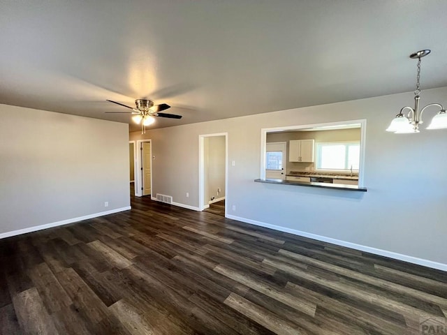 unfurnished living room with dark wood-style flooring, visible vents, a sink, and baseboards