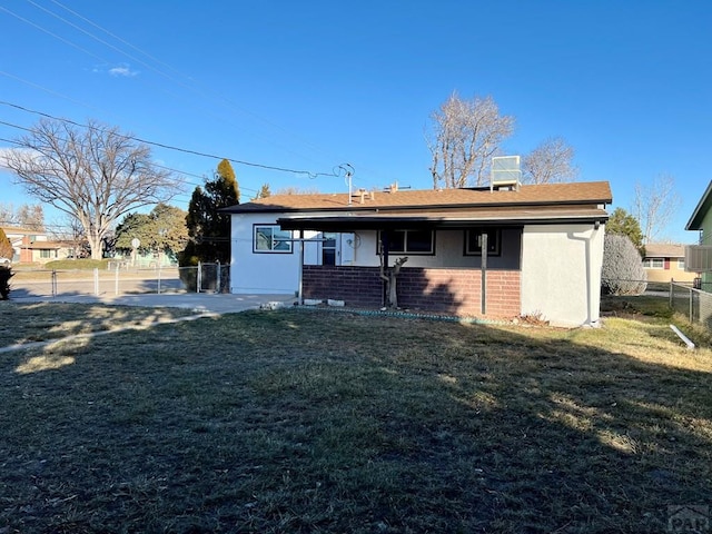 back of house with fence, a lawn, and brick siding