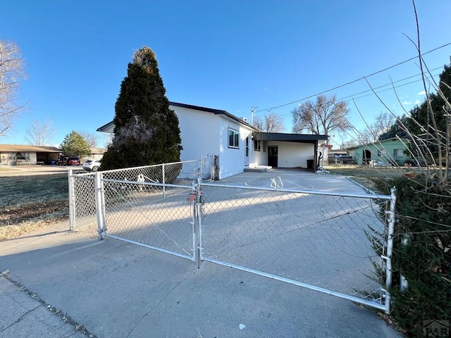 view of side of property featuring a gate, fence, and stucco siding