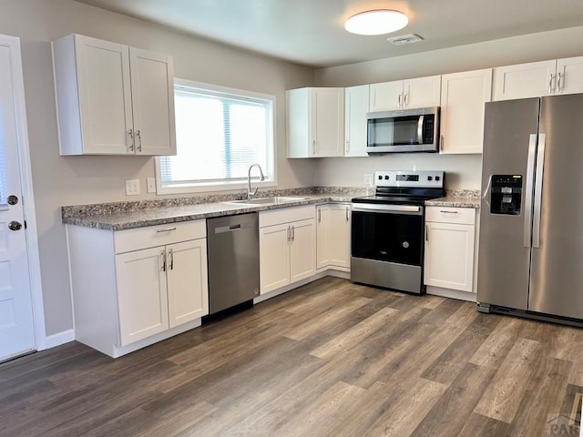 kitchen with stainless steel appliances, dark wood-style flooring, a sink, visible vents, and white cabinets