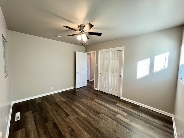 unfurnished bedroom with baseboards, visible vents, ceiling fan, dark wood-style flooring, and a closet