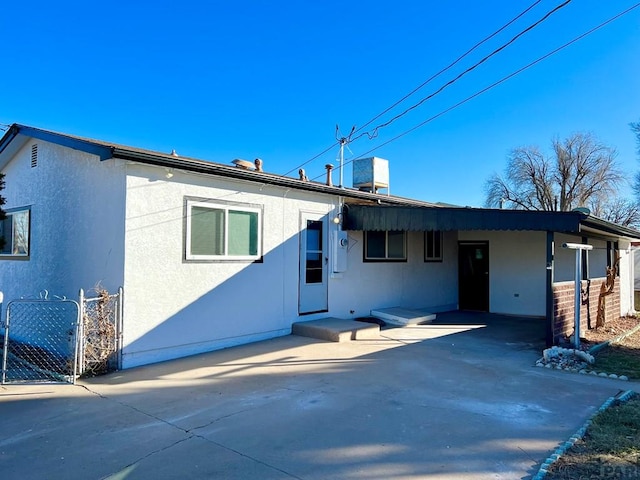 ranch-style house featuring a gate, concrete driveway, fence, and stucco siding