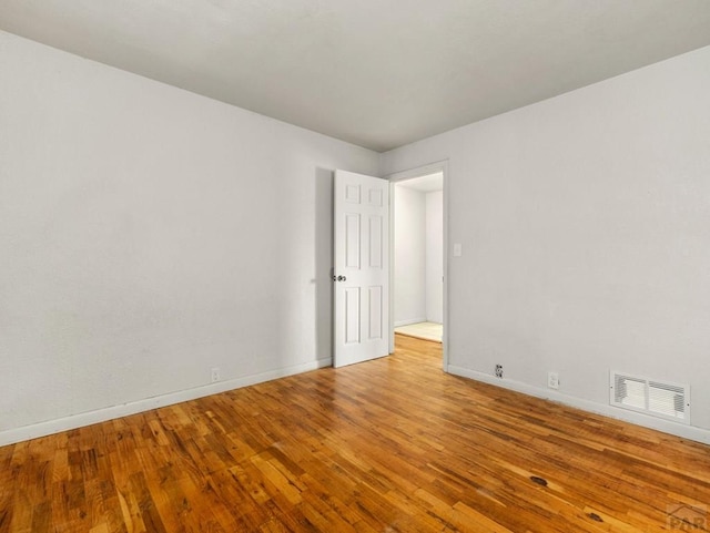 unfurnished room featuring light wood finished floors, baseboards, and visible vents