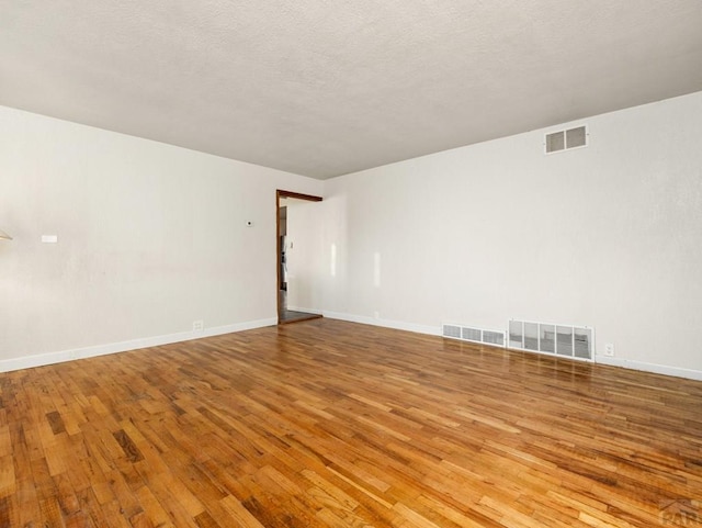 empty room featuring light wood-style floors, baseboards, and visible vents