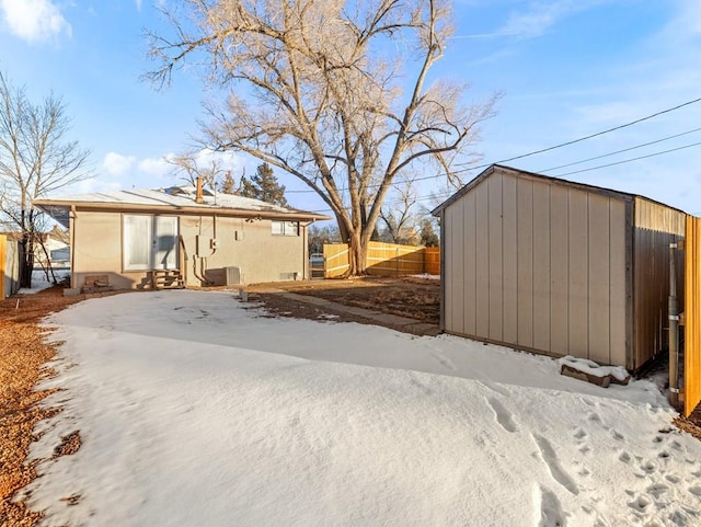 yard layered in snow with an outbuilding and fence