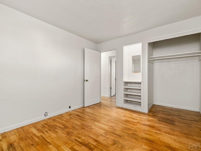 unfurnished bedroom featuring light wood-style floors, baseboards, and a closet