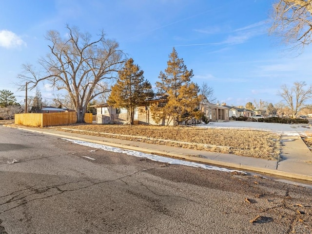 view of front of property featuring driveway, a residential view, and fence