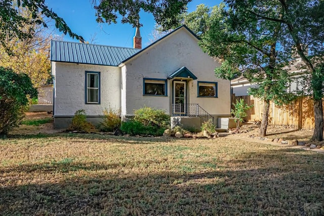 328 Colorado Ave, Walsenburg, CO 81089 - view of front facade with a front yard, a chimney, stucco siding, fence, and metal roof