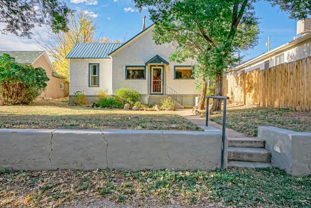328 Colorado Ave, Walsenburg, CO 81089 - view of front of home featuring a standing seam roof, stucco siding, fence, a front lawn, and metal roof