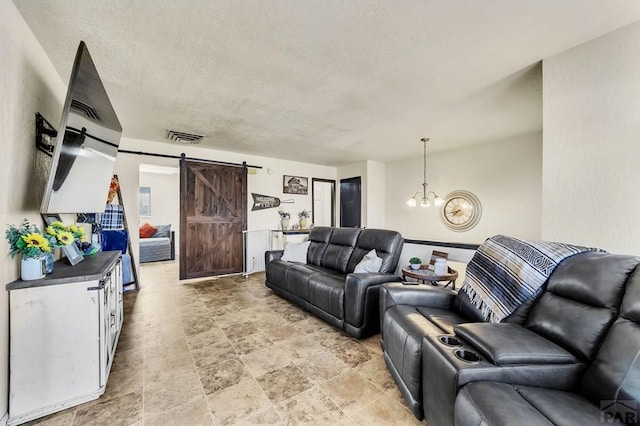 living room with visible vents, a textured ceiling, an inviting chandelier, and a barn door