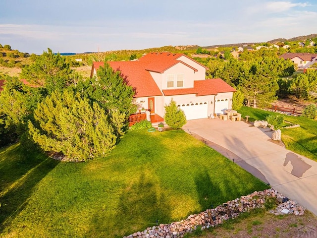 view of front of house featuring a garage, driveway, a front yard, and stucco siding