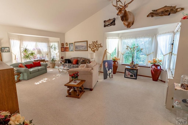 living room featuring light carpet, high vaulted ceiling, a wealth of natural light, and baseboards