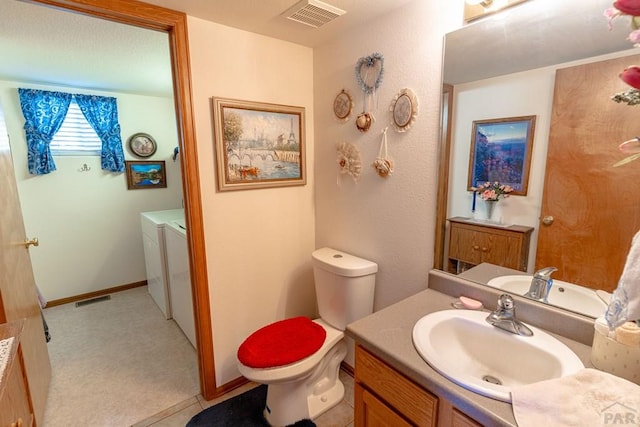 bathroom featuring toilet, washing machine and dryer, visible vents, and vanity