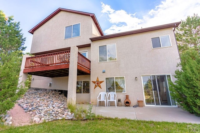 back of property featuring a deck, a patio, and stucco siding