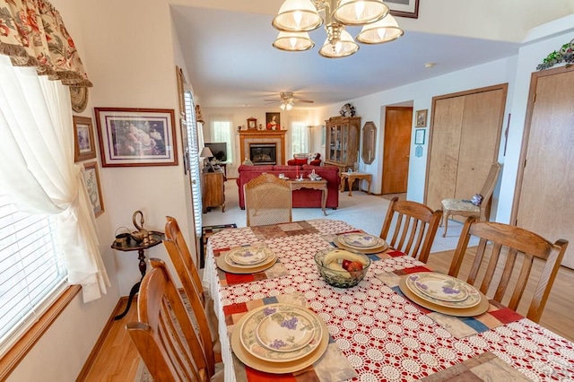 dining area with light wood-type flooring, plenty of natural light, and a glass covered fireplace