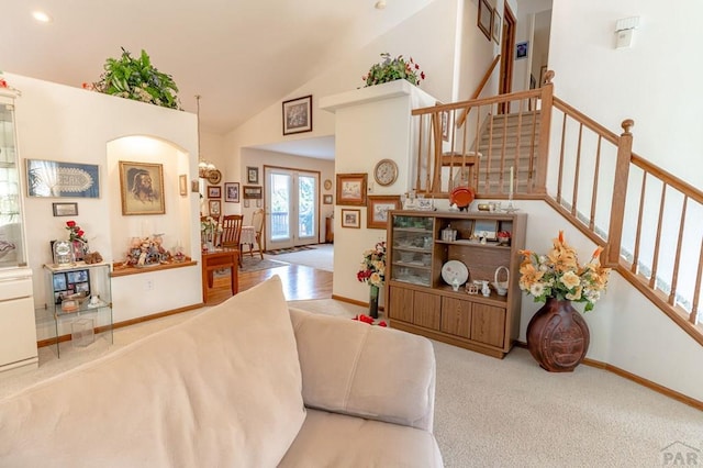 living room with baseboards, light colored carpet, stairway, french doors, and high vaulted ceiling