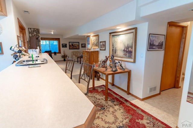 hallway featuring baseboards, visible vents, and light tile patterned flooring