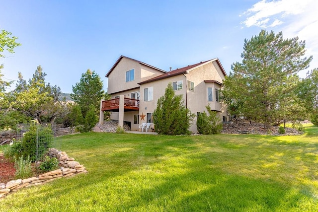 rear view of house featuring a deck, a yard, and stucco siding