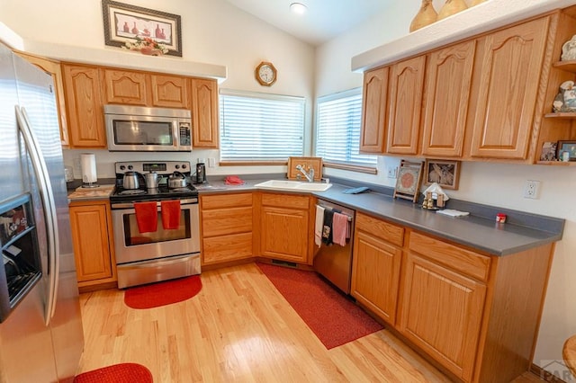 kitchen featuring dark countertops, lofted ceiling, stainless steel appliances, open shelves, and a sink