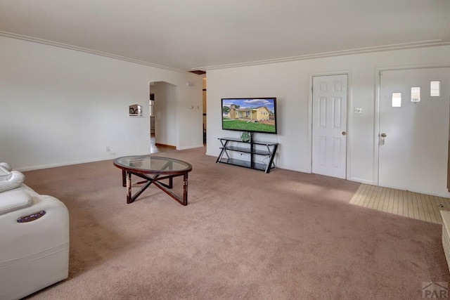 carpeted living area with arched walkways and ornamental molding