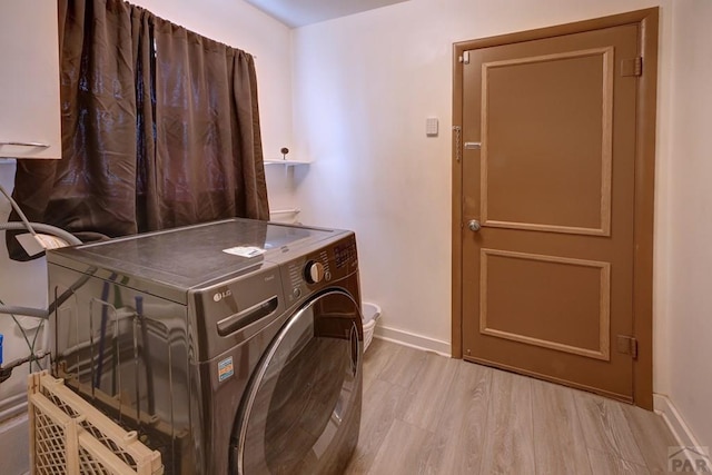 washroom featuring light wood-type flooring, washer / dryer, baseboards, and cabinet space