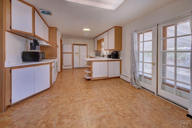 kitchen with white cabinetry, black microwave, and light countertops