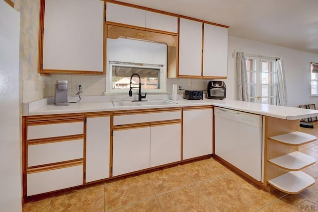 kitchen featuring white cabinets, white dishwasher, light countertops, and a sink