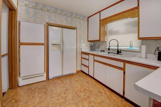 kitchen featuring white fridge with ice dispenser, a sink, light countertops, and white cabinetry