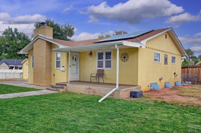 back of property featuring stucco siding, fence, and solar panels