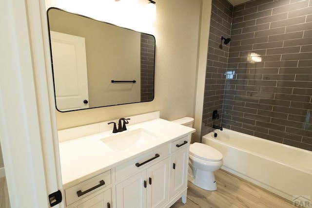 bathroom featuring toilet, wood finished floors, vanity, and washtub / shower combination