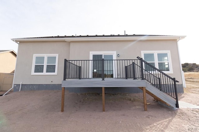 rear view of property with stucco siding and stairs