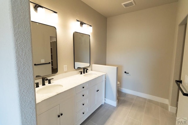 bathroom featuring double vanity, baseboards, visible vents, toilet, and a sink