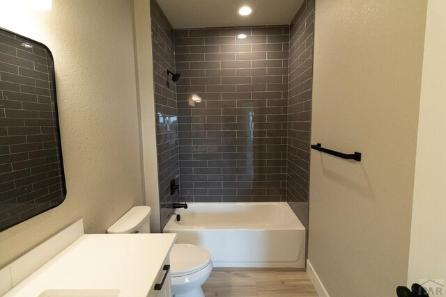 full bathroom with baseboards, toilet, wood finished floors, vanity, and washtub / shower combination