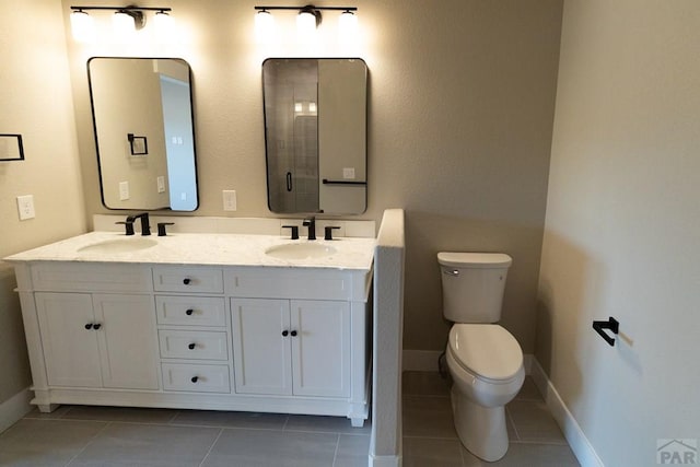 full bathroom with double vanity, tile patterned flooring, a sink, and toilet