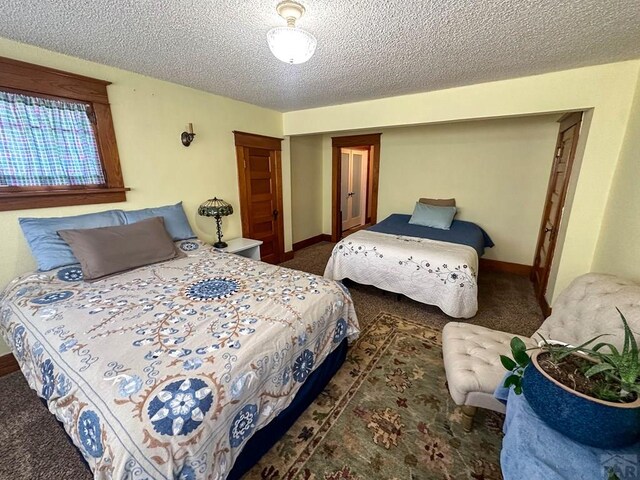 bedroom featuring baseboards, dark colored carpet, and a textured ceiling