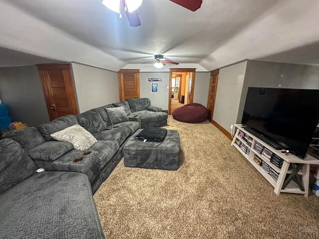 carpeted living room featuring baseboards, vaulted ceiling, and a ceiling fan