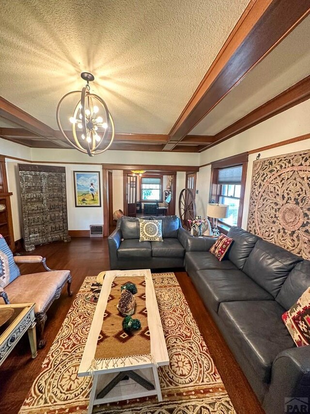 living area with a textured ceiling, a chandelier, dark wood-style flooring, and beamed ceiling