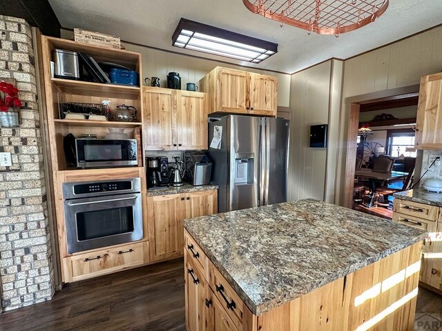 kitchen with a kitchen island, appliances with stainless steel finishes, dark wood-style flooring, dark stone countertops, and open shelves