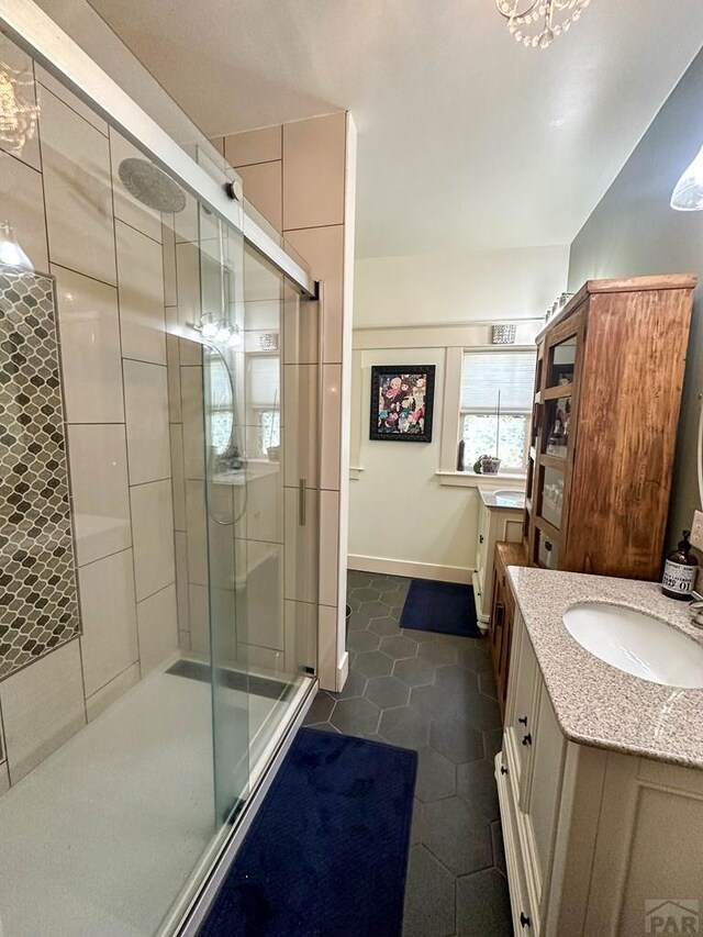 bathroom with a stall shower, vanity, and baseboards