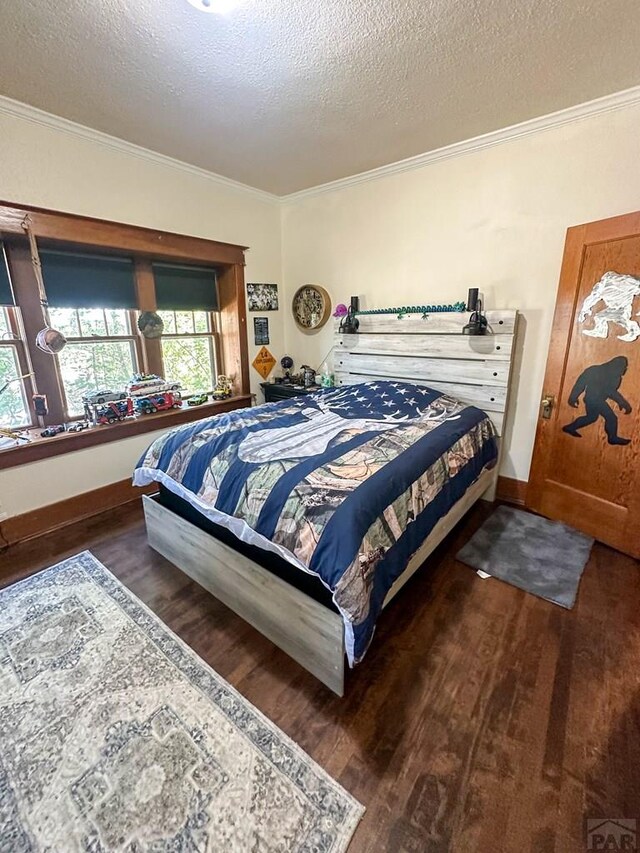 bedroom featuring dark wood-style floors, baseboards, ornamental molding, and a textured ceiling