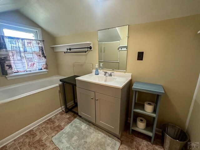 bathroom with lofted ceiling, a garden tub, and vanity